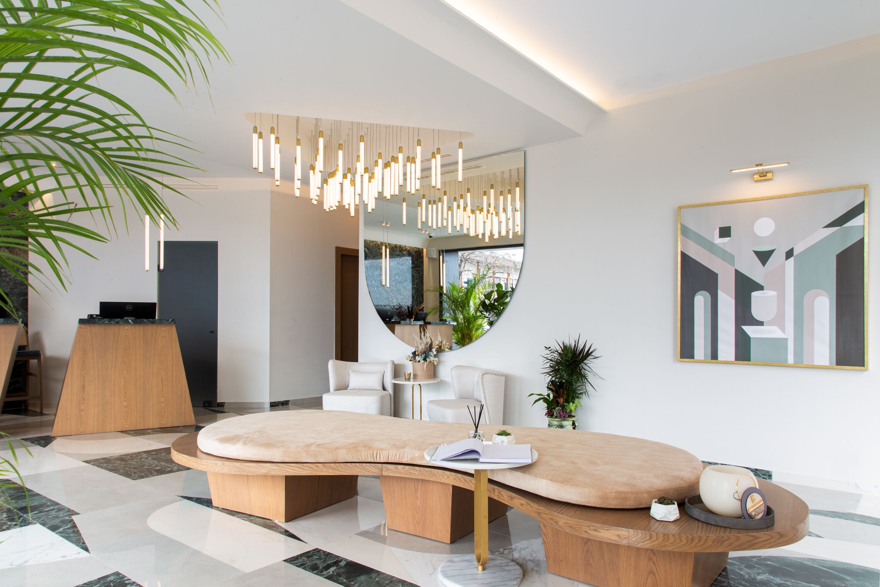 A modern reception area with a curved reception desk, a large mirror, and a hanging light fixture.