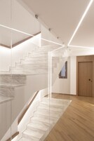 Una escalera moderna con barandillas de cristal y escalones de madera.