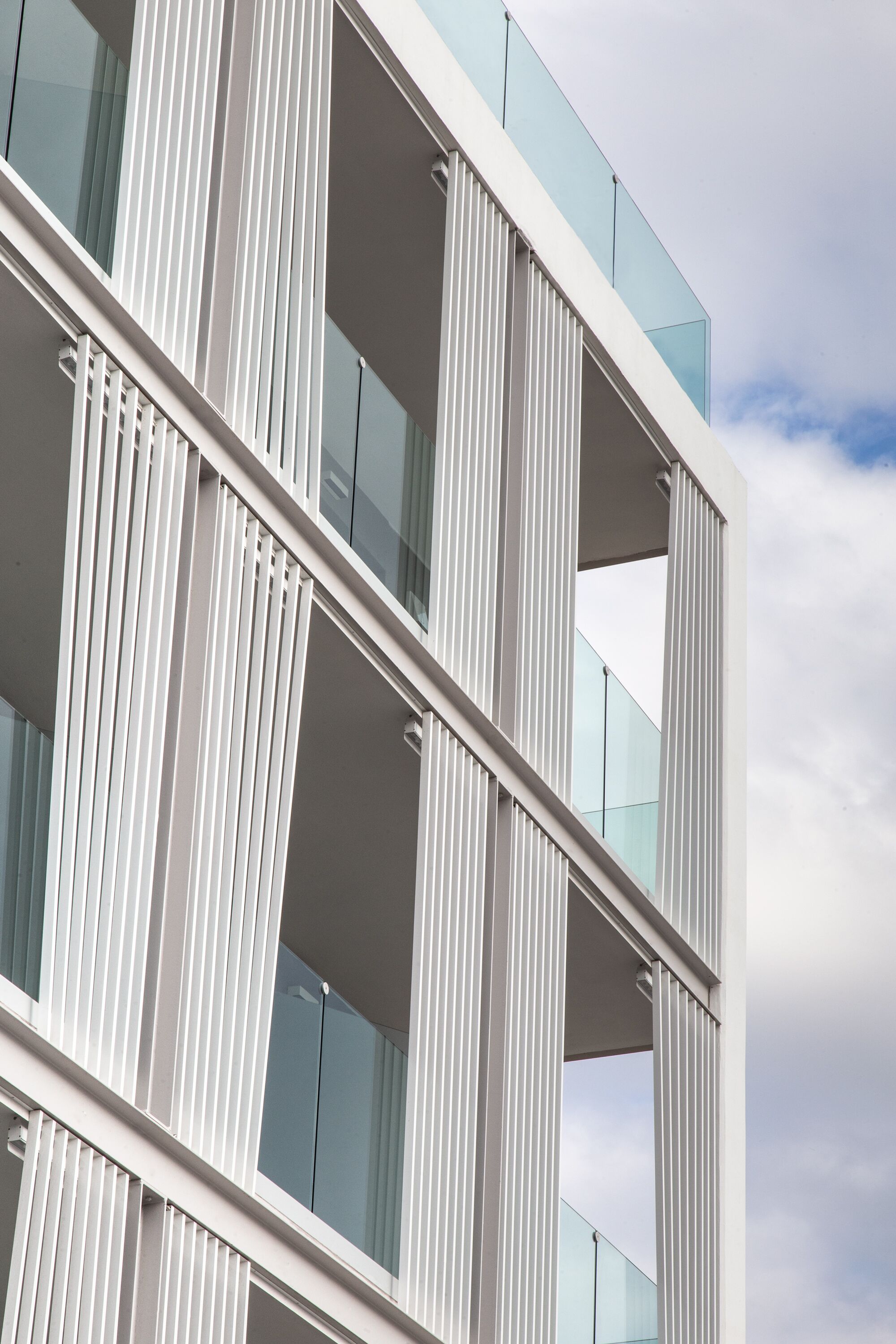 Un bâtiment moderne doté d’une façade en verre et de panneaux blancs verticaux.