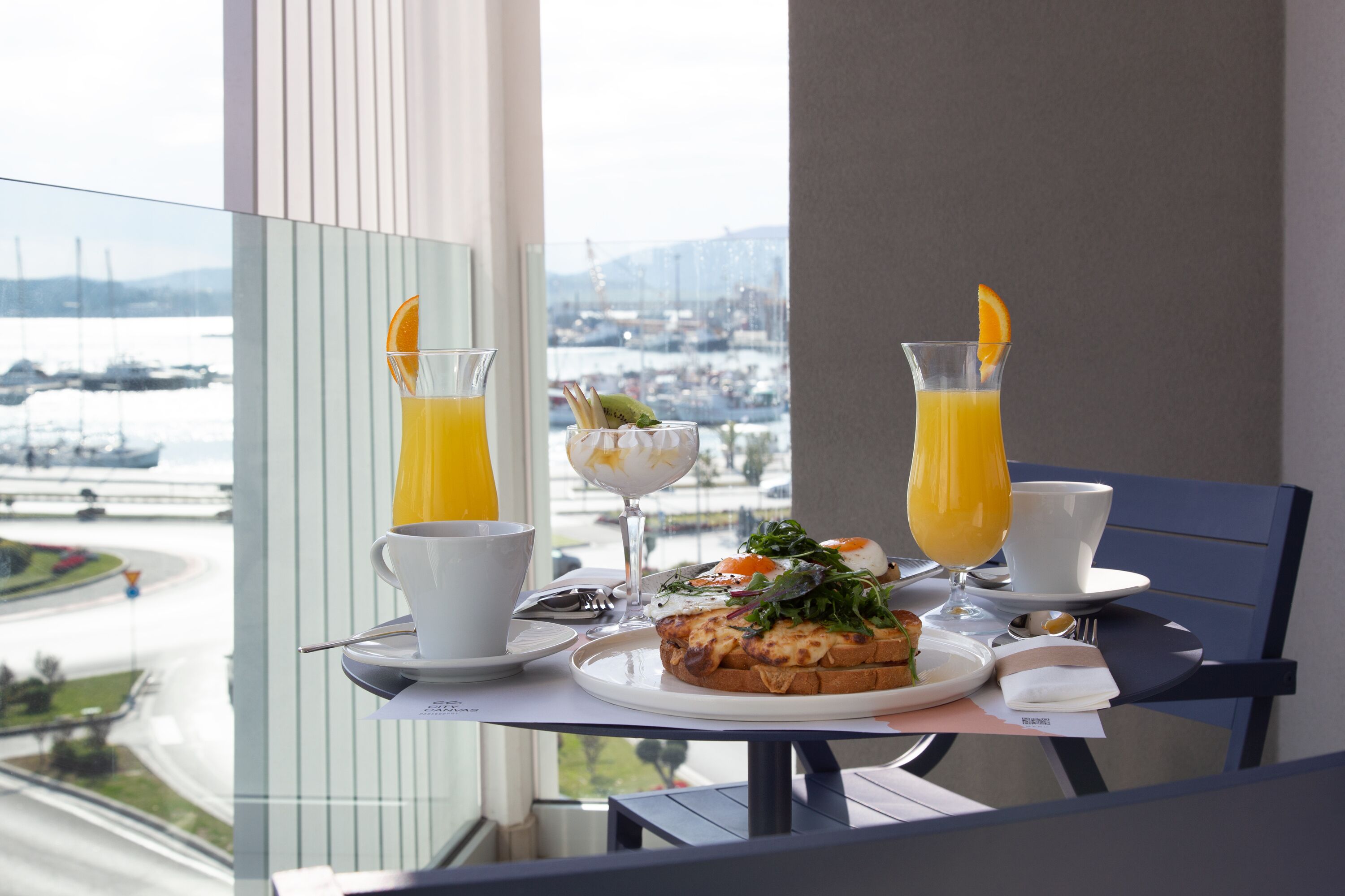 A breakfast table with a plate of food, two glasses of orange juice, a cup of coffee, and a glass of milk.