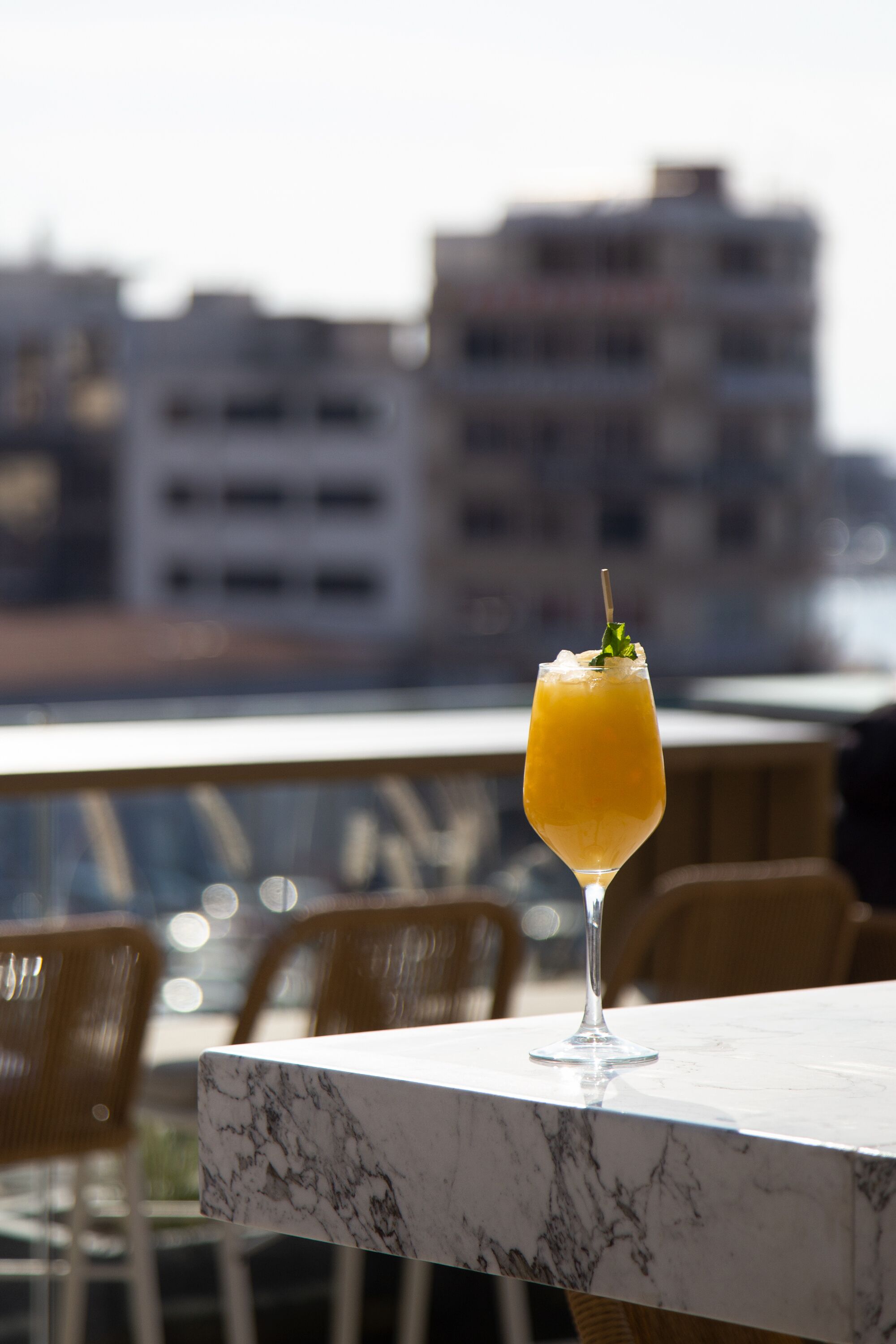 Un vaso de zumo de naranja sobre una mesa de mármol, con una vista urbana al fondo.