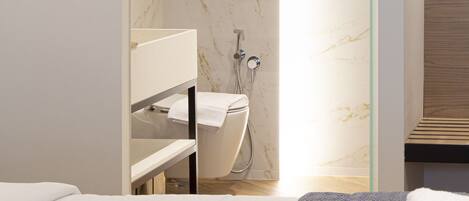 A modern bathroom with a glass shower enclosure, a white toilet, and a wooden vanity.
