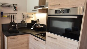 A modern kitchen with a Bosch oven, a coffee maker, and various utensils on the counter.
