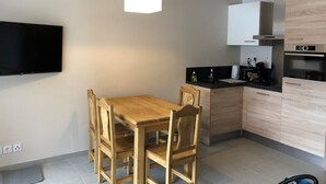 A compact kitchen with a wooden dining table and chairs, a black countertop, and a built-in oven.