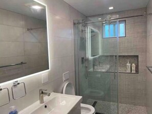 A modern bathroom with a glass shower enclosure, a large mirror, and a sink with a faucet. - Panoramic OceanView Getaway! Near SF, Beach & SFO (Daly City)