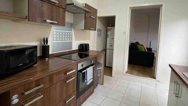 Una cocina con armarios de madera, microondas, cafetera y estufa.