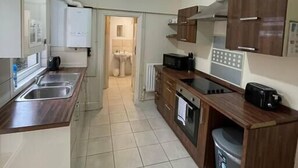 Una cocina moderna con una isla central, microondas integrado, horno y un pequeño contenedor de basura.
