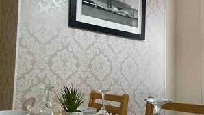 Una mesa de comedor dispuesta con platos, tazones y una copa de vino, con un cuadro de un puente en la pared.