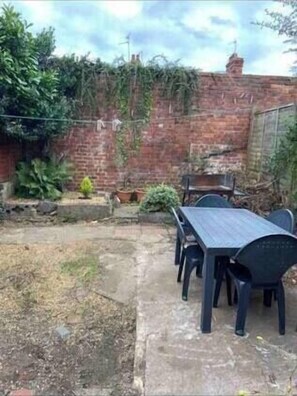Relax in the serene patio area with a long table and comfortable seating.