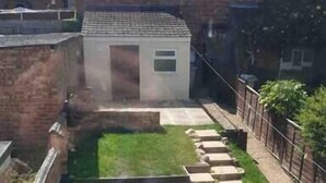 A courtyard with a small garden, a brick wall, and a pathway leading to a building. - Kettering Town Corporate - Ford Street (Kettering)