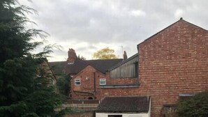 A residential property with a small garden, a brick house, and a white building with a window. - Kettering Town Corporate - Ford Street (Kettering)