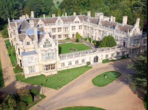 Un vaste manoir historique à la façade symétrique, doté de nombreuses cheminées et d’une cour intérieure.