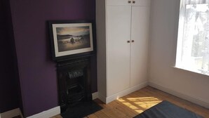 Quarto com lareira, um quadro emoldurado, guarda-roupa branco e janela com vista.