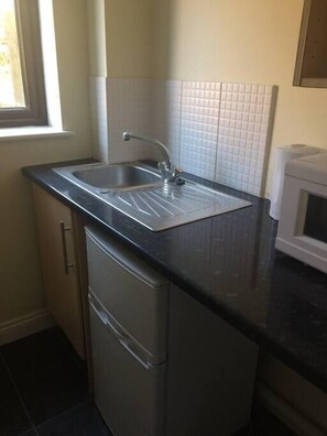A kitchen with a sink, a microwave, and a window.