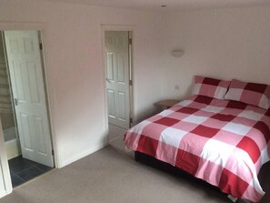 A bedroom with a checkered bedspread, a door, and a small bedside table.