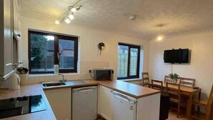 Eine kleine Küche mit Mikrowelle, Spüle und Geschirrspüler. Es gibt einen Essbereich mit Tisch und Stühlen.