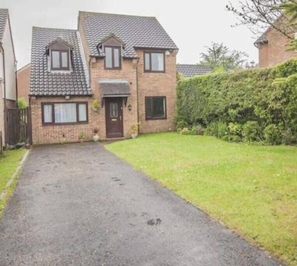 A two-story house with a paved driveway leading to the front door.