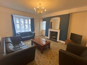 Ein Wohnzimmer mit Kamin, einer Couch, einem Couchtisch und einem Fernseher.