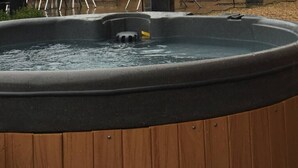 Ein Whirlpool mit Holzunterbau, umgeben von einer Holzterrasse.