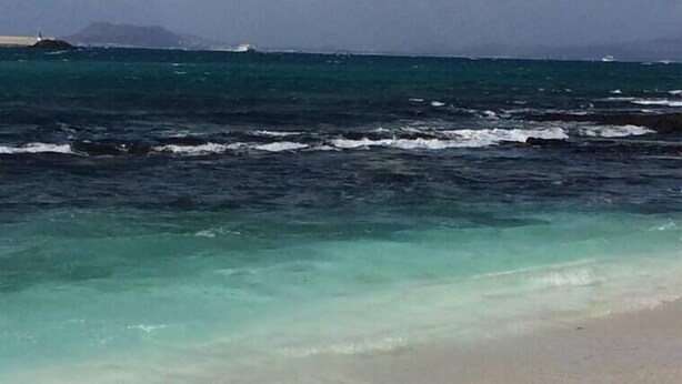 Une plage avec une eau claire et peu profonde et un rivage sablonneux.