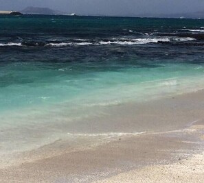 Ein Strand mit klarem, flachen Wasser und einem Sandstrand.