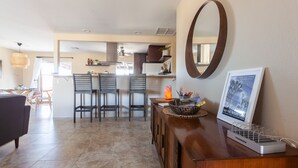 Cozinha moderna com área de jantar, um armário de madeira com régua de tomadas e uma moldura com imagem na parede.