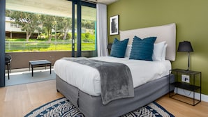A modern bedroom with a large bed, a view of a balcony, and a nightstand with a lamp. - FortyonL 709 (Cape Town)