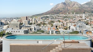 A rooftop pool with a "No Diving" sign, surrounded by a cityscape with buildings and mountains in the background. - FortyonL 709 (Cape Town)