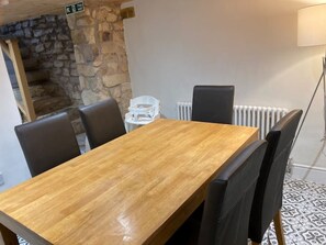 A wooden dining table with four chairs, a stone wall, a white radiator, and a patterned floor. - Instagram-ready 3 double-bedroom house next to castle and city (Lancaster)