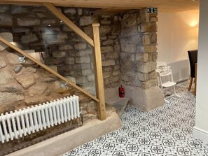 Cozy retreat with a stone wall, wooden staircase, and a comfortable chair.