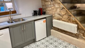 Una cocina compacta con pared de piedra, lavavajillas empotrado y radiador.