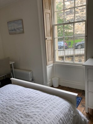 A bedroom with a large window, a radiator, a bedside table, and a bed. - Instagram-ready 3 double-bedroom house next to castle and city (Lancaster)