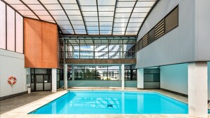 An indoor swimming pool with clear glass walls, a tiled floor, and a visible lifebuoy. - Micampus Rector Estanislao del Campo - Students Residence (Seville)