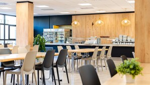 A modern cafeteria with wooden accents, metal chairs, and pendant lighting. - Micampus Rector Estanislao del Campo - Students Residence (Seville)