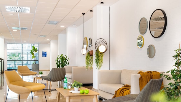 A modern lobby with seating, a coffee table, and decorative mirrors. - Micampus Rector Estanislao del Campo - Students Residence (Seville)