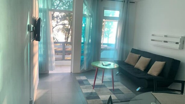 Een moderne woonkamer met een bank, een kleine ronde tafel en een uitzicht door grote ramen.
