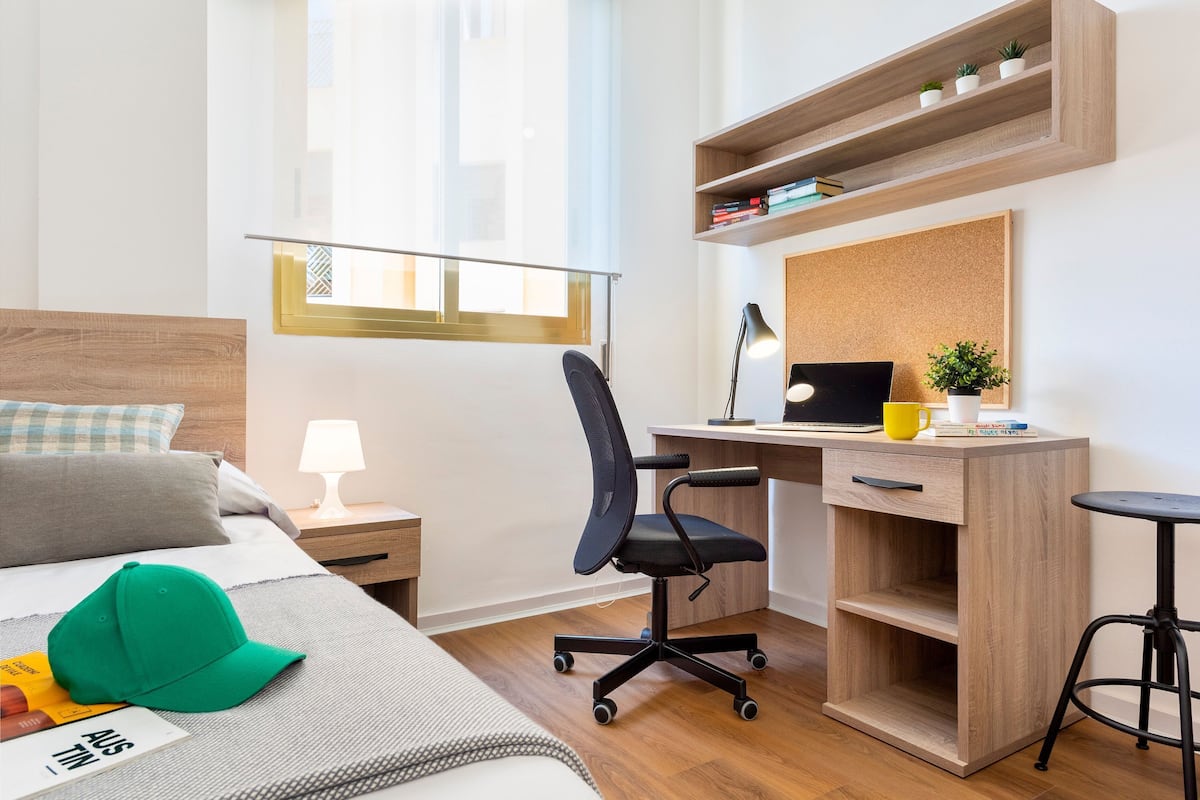 Ein modernes Hotelzimmer mit Bett, Schreibtisch, Stuhl und kleinem Tisch.
