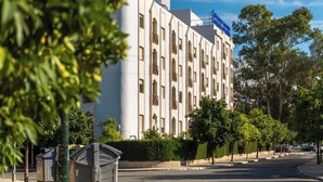 A large, white building with multiple windows and a blue sign on top. - Micampus Armendáriz - Students Residence (Seville)