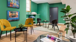 A modern living room with green walls, a black door, and two yellow chairs. - Micampus Armendáriz - Students Residence (Seville)