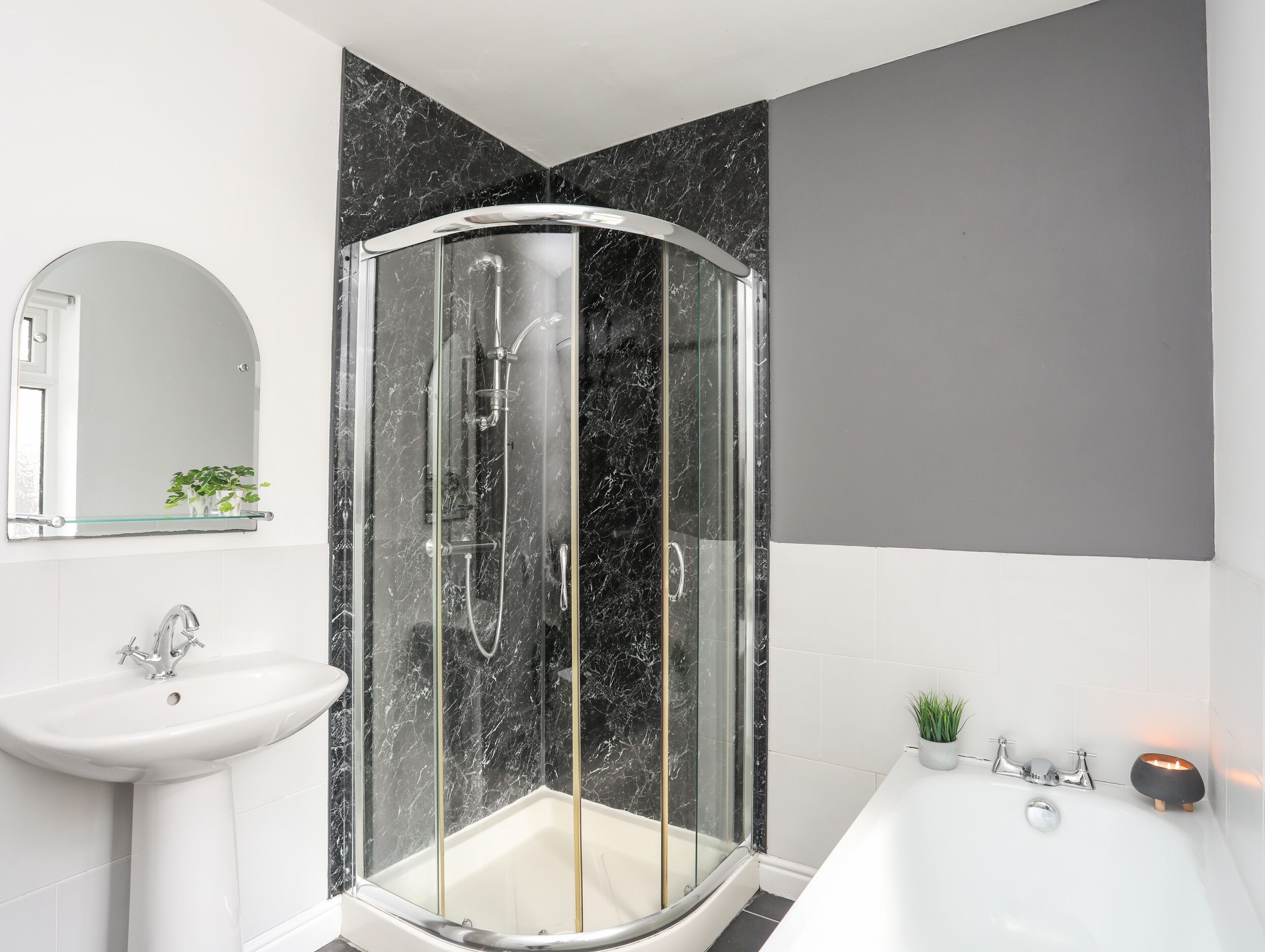Un bagno moderno con cabina doccia in vetro, un lavandino bianco e una vasca da bagno.