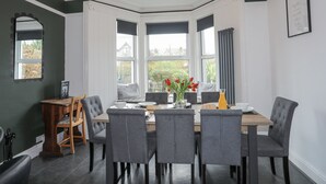 Een eetgedeelte met erker, een tafel gedekt voor vier personen, en grijze gestoffeerde stoelen.