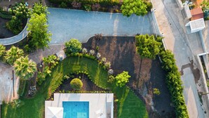 An aerial view of a modern house with a rectangular swimming pool, a well-maintained lawn, and a small garden area with various plants and flowers. - Villa Mediterranean Oasis (Rethymno)