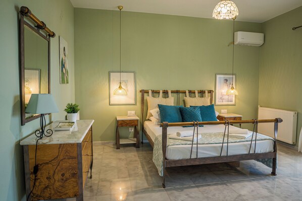 A bedroom with a wooden bed frame, a marble bedside table, a nightstand, and a hanging light fixture. - Villa Mediterranean Oasis (Rethymno)