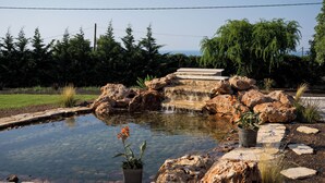 A landscaped garden with a pond, stepping stones, and potted plants. - Villa Mediterranean Oasis (Rethymno)