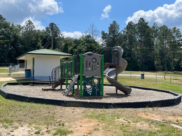 A playground with a slide, climbing structures, and a small shelter.