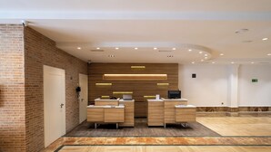 Un área de recepción con pared de ladrillo, mostrador de madera y suelo con patrón de espiga.