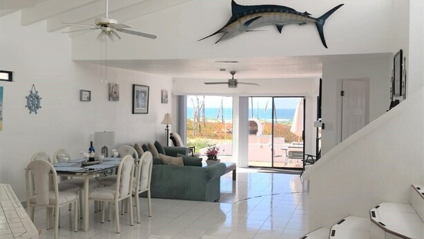 A spacious living area with a dining set, a green sofa, and a large fish mounted on the ceiling. - Mi Sueño Casita 2 - Directly on sandy beach (Ensenada)