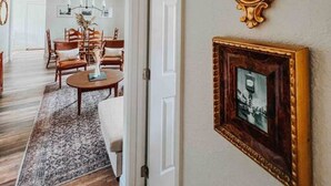 A spacious living room with a large wooden floor, a dining area with wooden furniture, and a hallway with a white door. - 3 Bedroom Modern Vintage in Historic Sanford (Sanford)