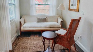A cozy room with a sofa, a small round table, and a wicker chair. - 3 Bedroom Modern Vintage in Historic Sanford (Sanford)