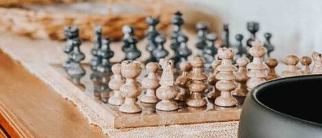 A chessboard on a wooden table with a black bowl beside it, in a room with a television mounted on the wall.